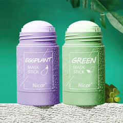 Green tea clay mask stick and eggplant mask stick packaging on a textured surface.