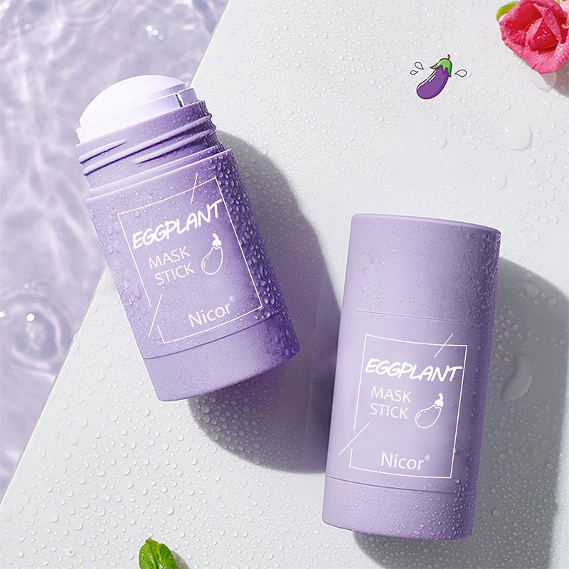 Eggplant mask stick by Nicor on a light surface with water droplets, highlighting its unique packaging and hydrating benefits.