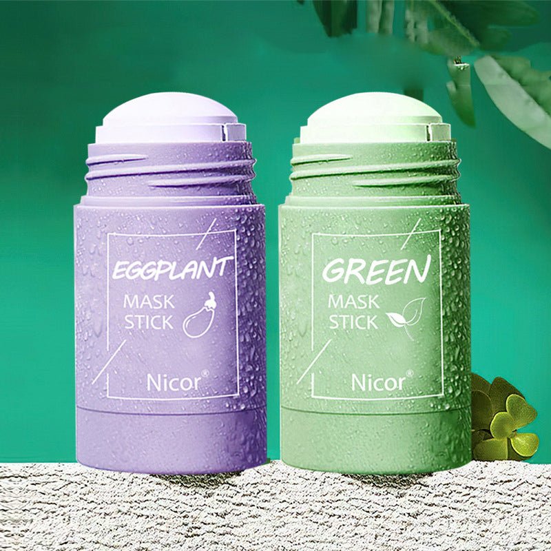 Green tea clay mask stick and eggplant mask stick packaging on a textured surface.